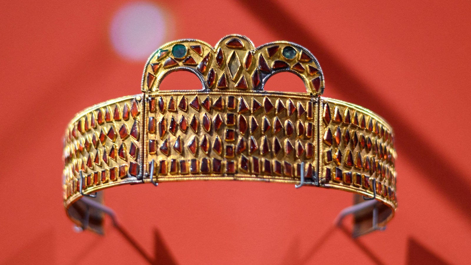 a garnet-studded gold crown against a red background