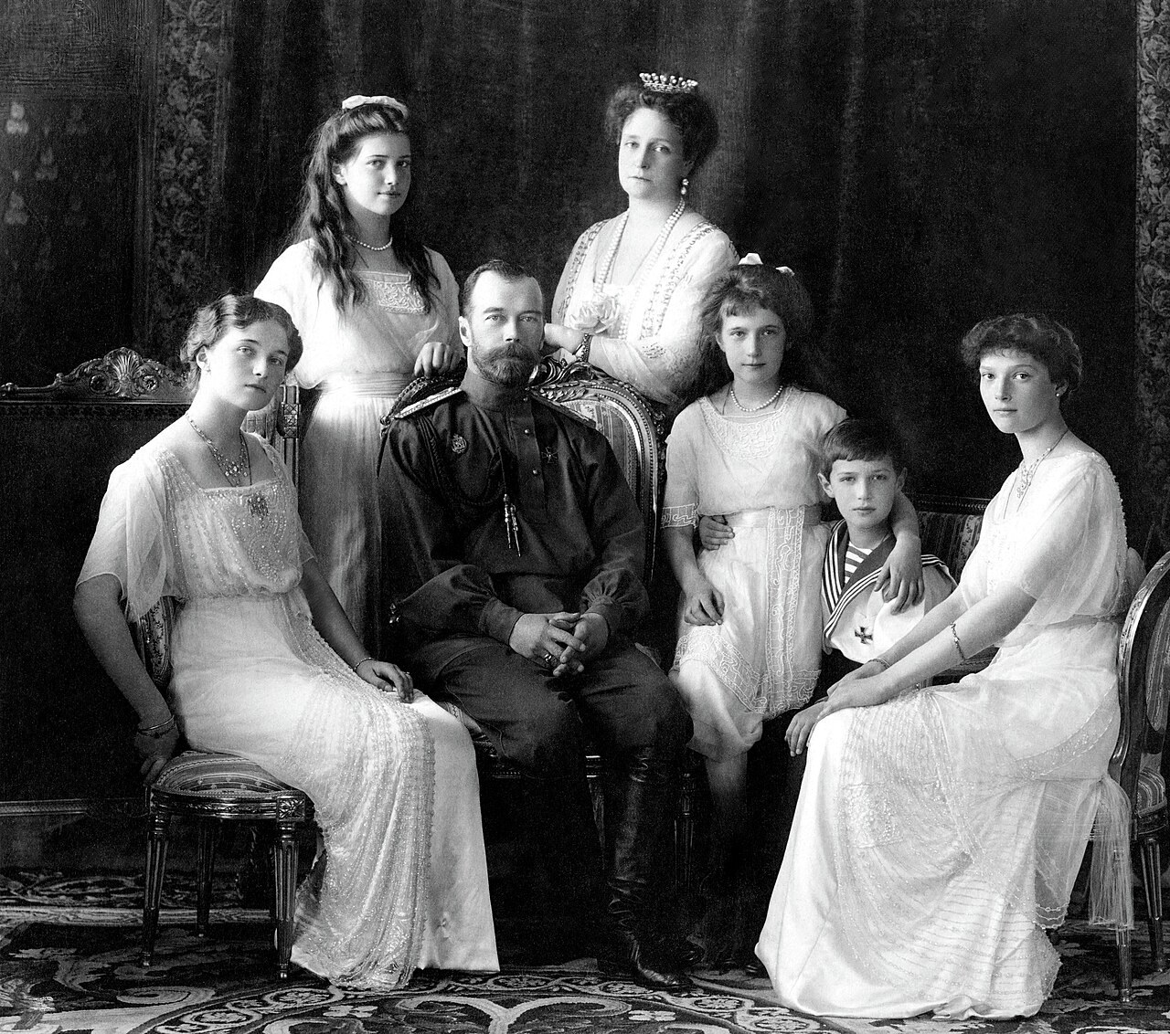 Formal studio portrait of a seated family group in white dresses and uniform