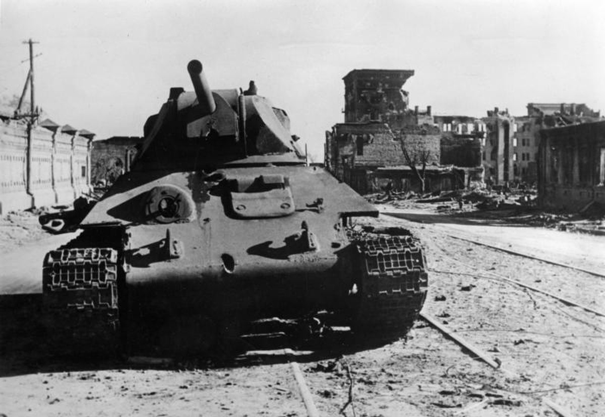 A knocked-out T-34 tank standing among rubble and wrecked buildings