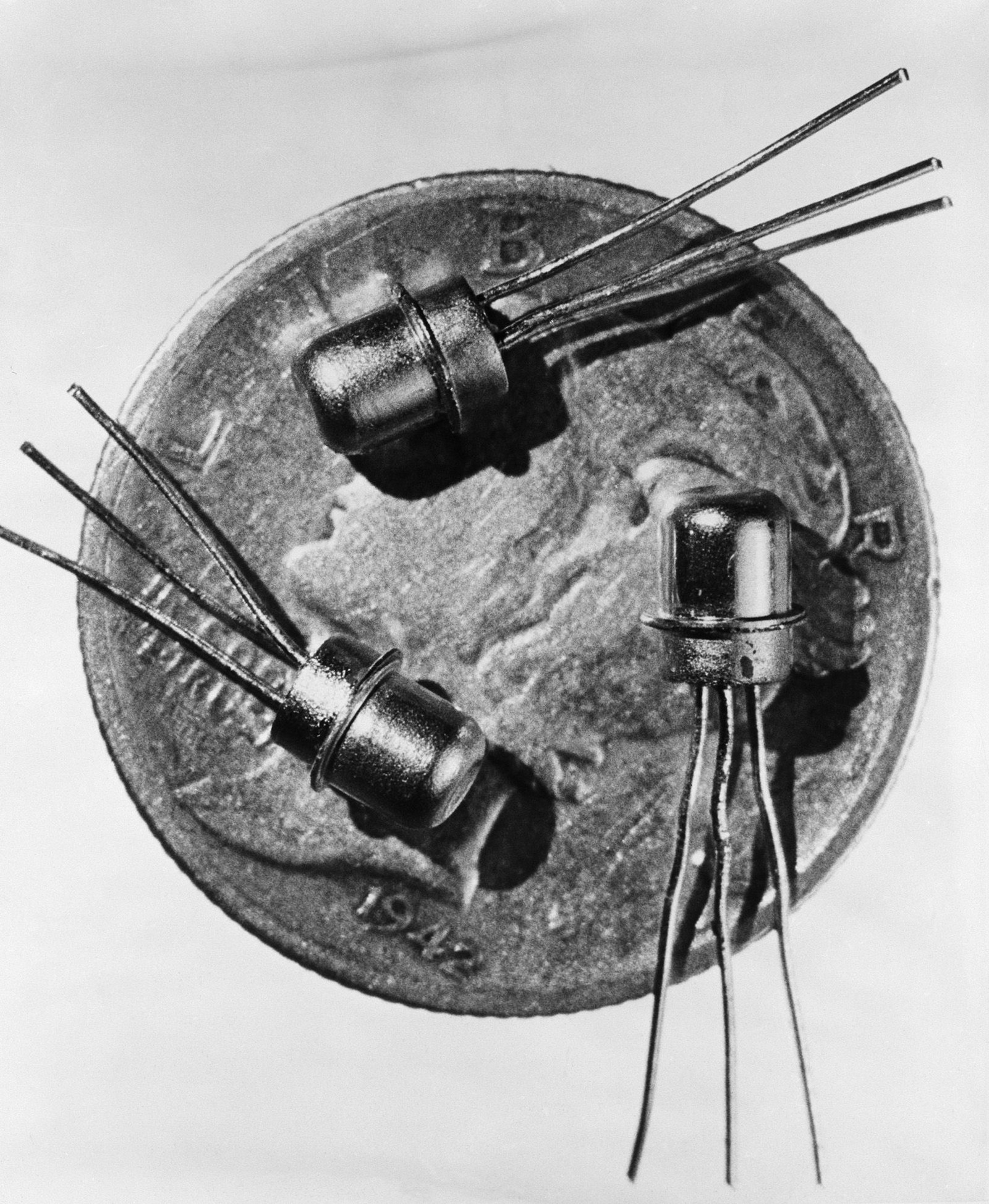 Three metal tubes with spikes coming off of them sit on a coin in a black and white photo