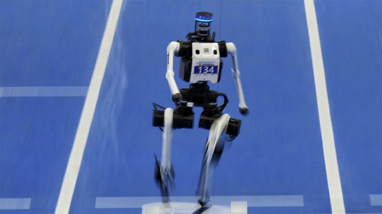 A humanoid robot runs on a blue track