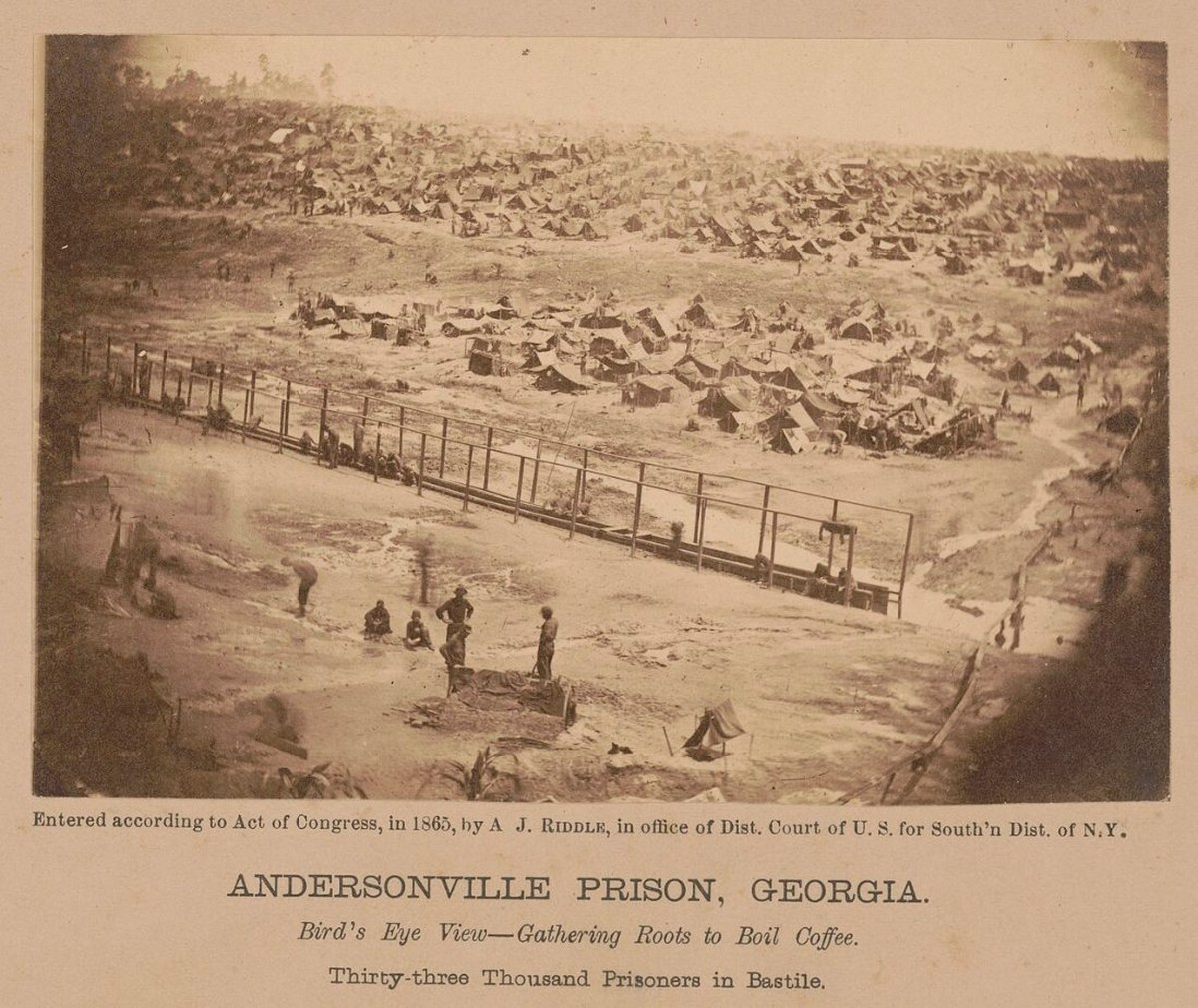 A bird's eye view of the prison in 1864, with the low dead-line rail running across the foreground and thousands of tents packed behind it