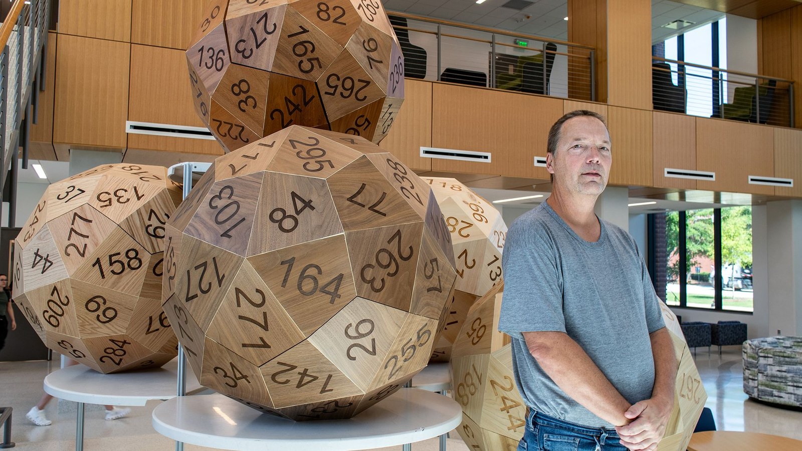 A series of large wooden dice sit next to a man