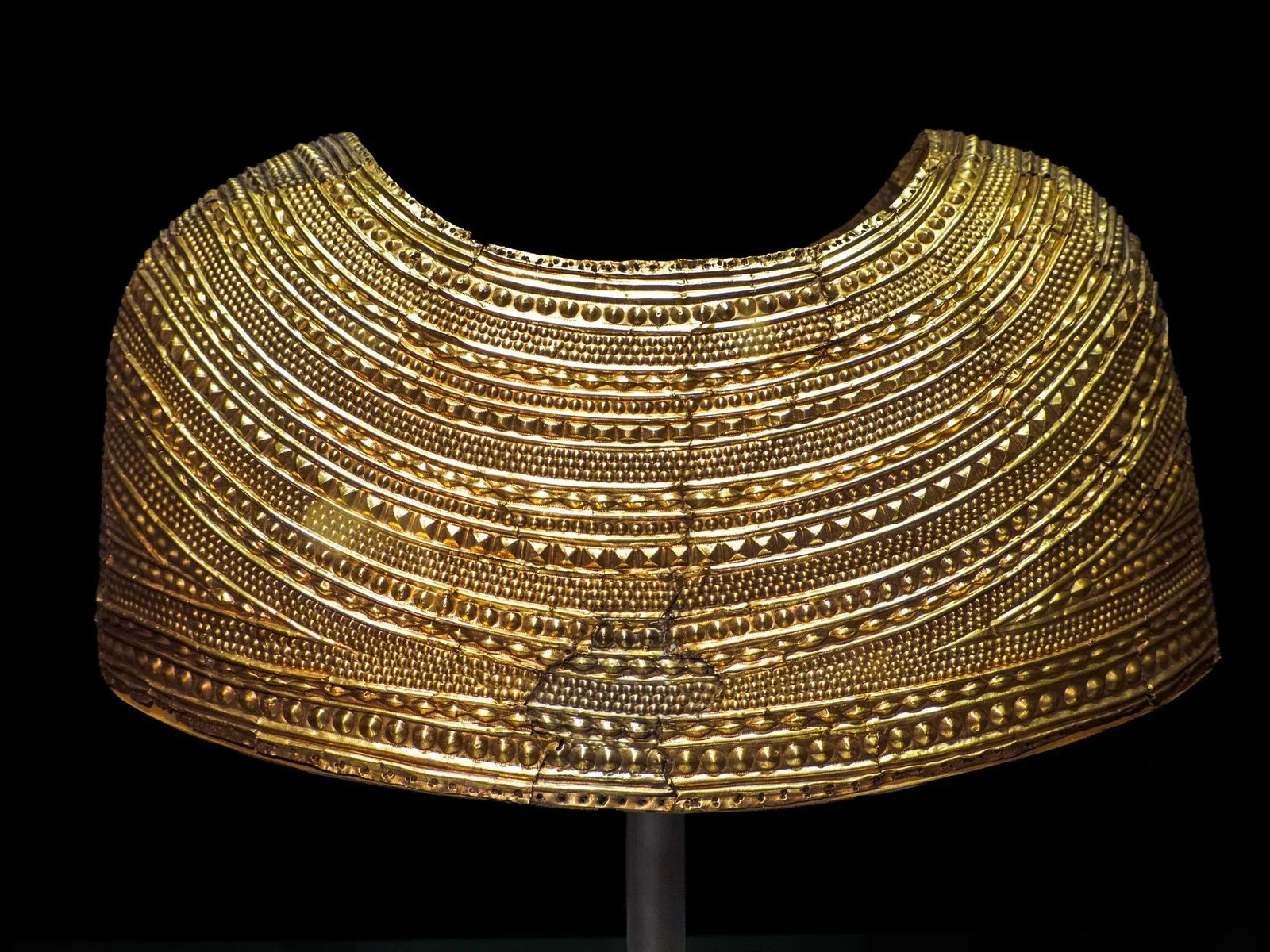 a gold accessory shaped like a cape against a black background